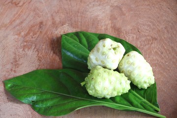 Noni fruit and Noni slice with leaf on old wooden table.Vegetable and Herb