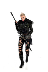 full length portrait of blonde girl wearing black gothic outfit, holding a staff. standing pose, isolated on white studio background.