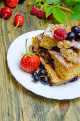 pieces of cake with berries and fresh strawberry currant and cherry berries on wooden background