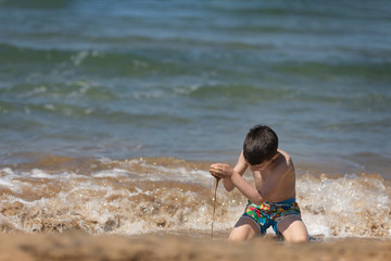 Young boy playing in the Ionian sea, Chalikounas beach, Corfu island, Greece
