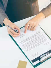 Businesswoman signs agreement contract in office.