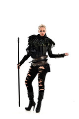full length portrait of blonde girl wearing black gothic outfit, holding a staff. standing pose, isolated on white studio background.