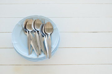 Empty Dish with spoon on white wooden table background.