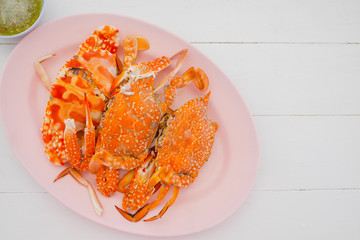 Special thaifood steamed crap claws on dish with spicy seafood saucebrown wooden table background.