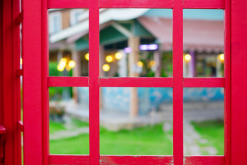 Fototapeta na wymiar Red wooden window with blurred nature background.