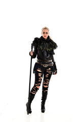 full length portrait of blonde girl wearing black gothic outfit, holding a staff. standing pose, isolated on white studio background.