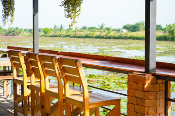 Fototapeta premium Wooden long bar table and chair with lotus water garden view.