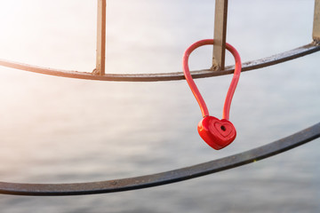 A padlock in the shape of a heart on a metal fence. A symbol of love and fidelity.