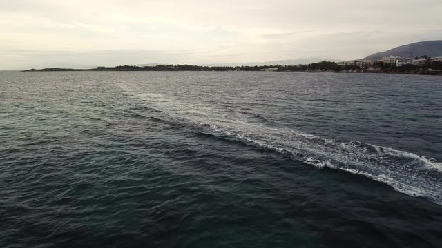 Flying over the sea on a cloudy day. Small island on the horizon.