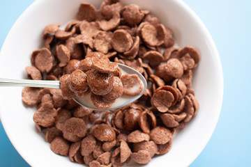 Bowl of cereal chocolate flavor and milk breakfast with silver spoon