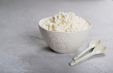 Plate of homemade cottage cheese with ceramic  spoons. On gray concrete background.