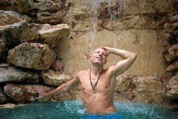 Man enjoying waterfall in swimming pool