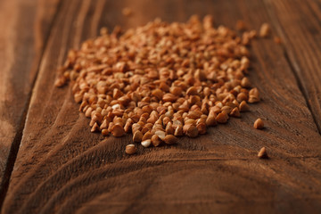 Wooden Board . On the Board scattered brown grain buckwheat.