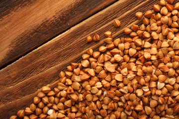 Wooden Board . On the Board scattered brown grain buckwheat.