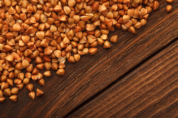 Wooden Board . On the Board scattered brown grain buckwheat.