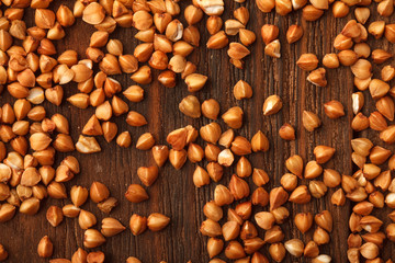 Wooden Board . On the Board scattered brown grain buckwheat.