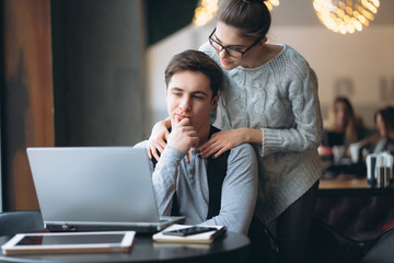 Beautiful couple watching on the laptop in the cafe.