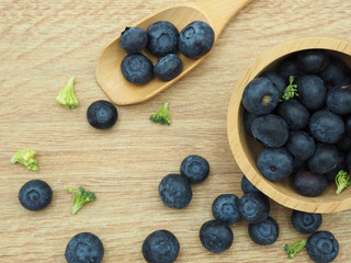Fresh blueberry with spoon on wooden background. Healthy food and diet.