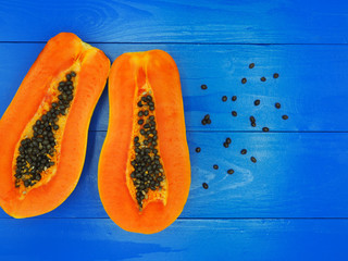 Fresh sliced half papaya isolated on blue wood background.