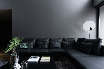 Cozy black leather sofa in composition with minimal black and white floor lamp with gray painted...