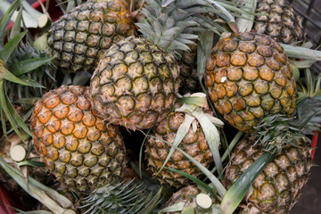 Pile pineapple fruit which has been harvested and display for sale on farmers table in market. 
