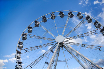 Ferris wheel under blue sky and white clouds in a village fair market