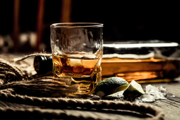bottle of rum whiskey bourbon and a glass with ice on a wooden background