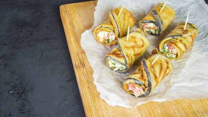 Rustic grill fried eggplant rolls stuffed with melted cheese, tomatoes and fresh garlic on a wooden board