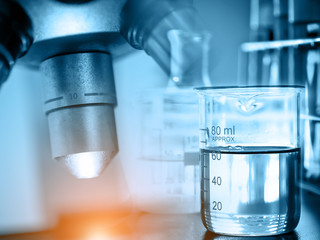 microscope with lab glassware, science laboratory research and development concept