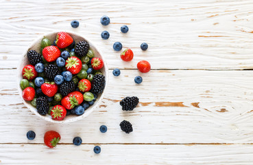 Fresh juicy ripe berries in a white plate-strawberries, blueberries, blackberries and gooseberries