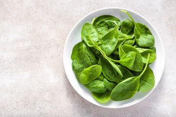 Green leaves of spinach on plate, healthy diet, vegan food concept