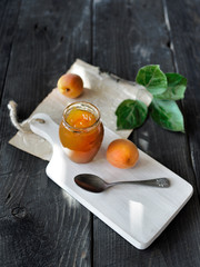 Fresh apricots and apricot jam in jar on rustic wooden table. Copy space.