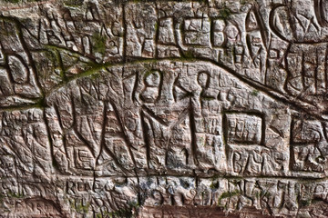 Natural cave in sandstone rock, former bank of Gauja river. Carved wall in Gutmanis cave in...