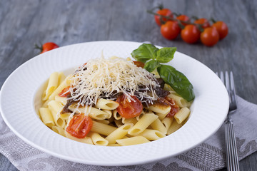 Pasta with cherry, tomato-basil sauce and parmesan on white plate.