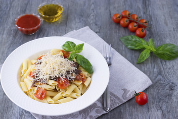 Pasta with cherry, tomato-basil sauce and parmesan on white plate.