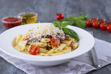 Pasta with cherry, tomato-basil sauce and parmesan on white plate.