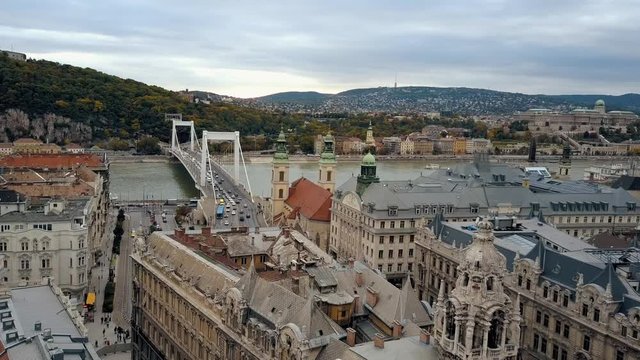 Long drone shot over a busy European city flying between two steeples and over the river.