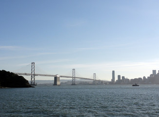 Tugboat heads towards Bay Bridge with San Francisco Downtown cityscape in the background