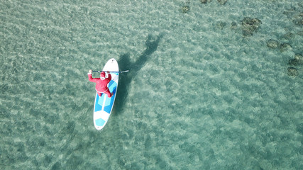 Aerial drone of Santa Claus paddle surfing in Caribbean turquoise clear waters
