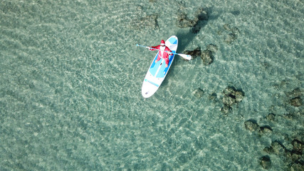 Aerial drone of Santa Claus paddle surfing in Caribbean turquoise clear waters