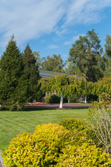 various coniferous and deciduous trees and bushes planted in a park with walking paths