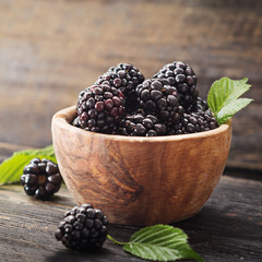 Blackberries in wooden bowl on old dark table with free text space.  Agriculture, Gardening, Harvest Concept. Selective focus.