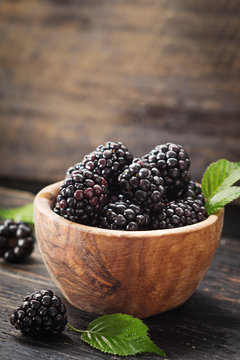 Blackberries in wooden bowl on old dark table with free text space.  Agriculture, Gardening, Harvest Concept. Selective focus.