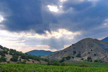 Naklejka premium The tops of a rocky green mountain range against a cloudy sky background