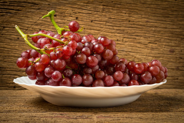 grapes seedless red on dish on old wood