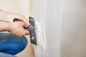 Spatula with putty in hands. Worker puts of plaster on wall.