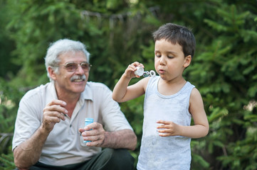 Obraz premium grandfather with grandson blowing soap bubbles