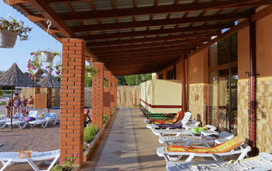 chaise lounges with towels on the porch under the awning