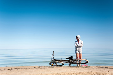 Young sporty lady resting from riding bicycle on the beach