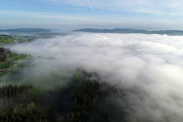 Aerial view of the hilly landscape in central Switzerland on a beautiful spring morning with some morning fog